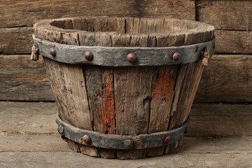 Poster - Rustic wooden bucket with metal bands displayed on a wooden surface in a charming vintage setting