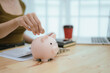 © Dara-Sroi - Woman putting money in piggy bank, money saving concept