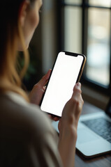 Poster - A woman sitting in front of a laptop, holding her cell phone for reference