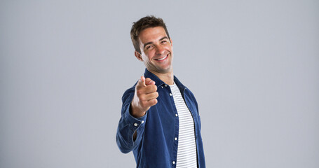Poster - Portrait, pointing to you and man in studio, smile and choice with confidence on white background. Face, happy person and model with hand gesture, opportunity and decision with sign up and selection