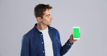 Poster - Man, hand and phone with green screen in studio for advertising on white background. Male person, model or user with mobile smartphone display, chromakey or new app for marketing on mockup space