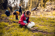 © Marko Geber - Young girl and family picking up litter in a forest during a hike