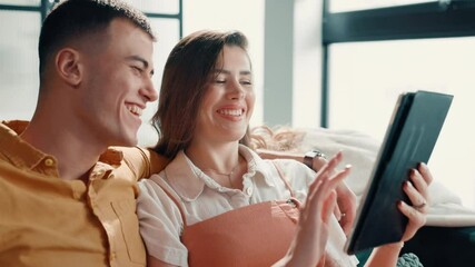 Poster - Couple, laughing and scroll with tablet on sofa for social media meme, funny post or comedy video. People, bonding together and pointing to digital app in home for web browsing and streaming service