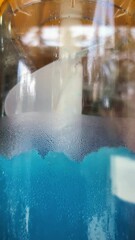 Poster - Condensation developing on glass jar exterior, revealing textured surface against deep blue liquid interior