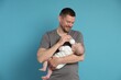 © New Africa - Father feeding his little baby with bottle on light blue background