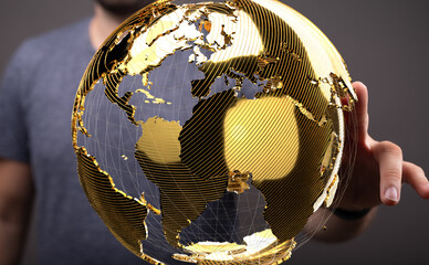 Fototapete - A hand holds a golden globe, symbolizing global connectivity and international business.