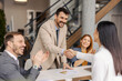 © Dusan Petkovic - Smiling executive shaking hands with successful businesswoman at corporate office while colleagues applauding.