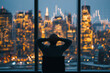 © Igor - Rear view of sitting businessman who is looking at the city from the modern panoramic office. New York evening view. Crossed hands on the head. Financial charts are drawn over the panoramic windows