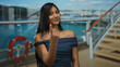 © Krakenimages.com - Woman gesturing come hither with finger aboard cruise ship capturing outdoor scenery of ocean and sky with latin style in vibrant daylight atmosphere