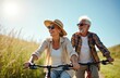 © miss irine - Happy senior couple ride bikes outdoors. Man and woman enjoy sunny day on bikes. Elderly people smile, wearing sunglasses. Happy active mature lifestyle. Retirement vacation in nature.