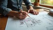 © miss irine - Architect sketches residential blueprint with pencil on drawing. Architect hands work with floor plan, project design. Concept of building construction, engineering, architecture, drafting and design.