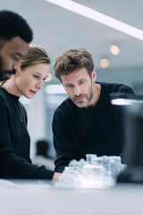 Poster - Diverse team analyzing a complex prototype or architectural model, symbolizing innovation, collaboration, and strategic planning in a modern setting.