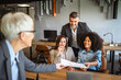 © Miljan Živković - Confident senior businesswoman share documents with colleagues