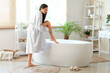 © Pixel-Shot - Beautiful young happy woman in bathrobe shaving legs at home