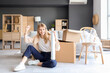 © Pixel-Shot - Young woman with stretch wrap sitting in room on moving day