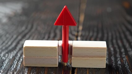 Poster - Red Upward Arrow Bisecting Stacked Blocks on Dark Brown Wooden Surface Symbolizing Progress And Growth