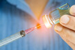 © Photo Sesaon - doctor's hand holds a syringe and a blue vaccine bottle at the hospital. Health and medical concepts.