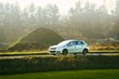 © AlexGo - Modern hatchback driving on a road near trees drive on a sunny day
