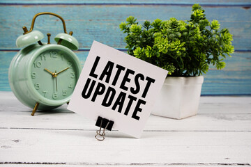 latest update text written on paper card with alarm clock on wooden background