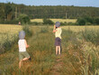 © Natallia - Two young boys walking along a narrow path in a rural field on a sunny summer day. One of them is looking through binoculars. Natural countryside landscape with golden grass, wildflowers, and trees.