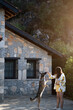 © mehmetugurozer - A young woman trains her dog to jump in a sunlit summer garden with a stone house