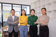 © SOMKID - Group of Asian businesspeople look at camera together standing in modern office, Business startup and company strategy planning concept.