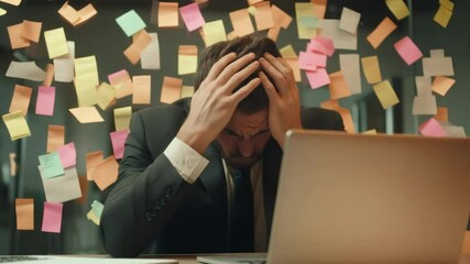 Poster - Stressed businessman in a suit massaging his head at an office desk, surrounded by a wall covered in colorful sticky notes, working late into the night with a laptop open