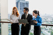 © Jack Tamrong - Businessman and two female colleagues holding laptop working together at high rise office balcony