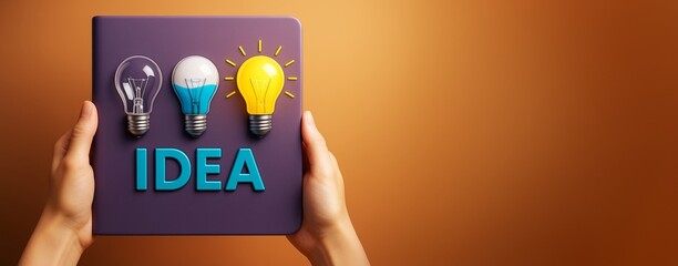 Poster - Hands holding creative idea concept book with colorful light bulbs on cover against warm background, symbolizing innovation and inspiration.