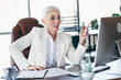 © deagreez - Confident mature businesswoman in professional attire speaking at office desk, showcasing leadership and expertise