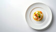 © Panarat - the image shows a carefully arranged food dish on a large, round, white plate. a light yellow puree is arranged in a circle in the center of the plate