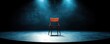 © kokoson6 - A single wooden chair sits center stage under dramatic blue spotlights in a dark, empty theater.