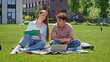 © stockbusters - Smiling couple learning nature sitting green university campus lawn. Two friends