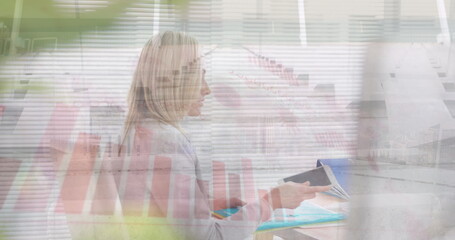 Poster - Image of caucasian businesswoman working at desk over graphs