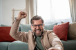 © Migma_Agency - Excited man celebrating success at home raising fist