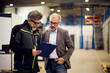 © bnenin - Two Professionals Discussing a Project in a Modern Warehouse Interior