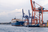 Bosphorus harbor with cargo ship and cranes during cloudy weather at dusk