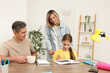 © New Africa - Smiling parents helping their daughter with homework at table indoors