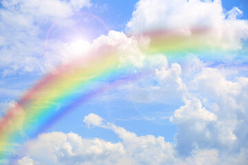 bright rainbow in blue sky with clouds on sunny day