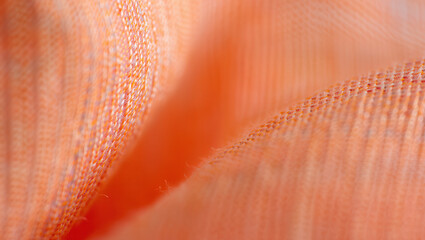 Poster - Close up shot of soft orange fabric with a textured weave pattern and blurred background effect