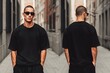 © Aleksander - A stylish young man wearing a black oversized t-shirt mockup and sunglasses, standing confidently in an urban alley. The photo captures both front and back views, showcasing modern street fashion.