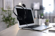 © New Africa - Headset with microphone and laptop on white wooden desk in office