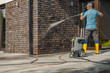 © Tomasz Zajda - Man Using Pressure Washer to Clean Brick Wall of Modern House During Daytime