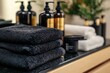 © Opi - Stack of black towels and hair care products, A stack of black towels alongside various hair care products arranged neatly on a countertop