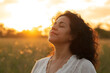© Rattanapon - A serene Latin woman enjoying the sunset with gratitude