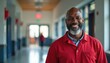 © Pete - Smiling middle-aged Black man, school service worker in red uniform. American public elementary school hallway, friendly, professional staff member. Education, community, welcoming atmosphere.