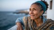 © Pinklife - A joyful woman in a blue turban stands beside the sea, her warm smile and elegant attire reflecting a deep connection with nature, radiating tranquility and contentment.