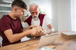 © Migma_Agency - Grandfather and grandson opening a package together at home