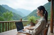 © Pete - Young asian woman works on laptop computer on wooden balcony with mountain background. Female freelancer, remote worker enjoying work in nature. Technology, travel, vacation, business, lifestyle,
