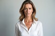 © Pete - Serious middle aged woman in studio portrait. Sad, angry face expression. Mature female wearing white shirt. Portrait of upset, displeased, unhappy person. Isolated on seamless white background.